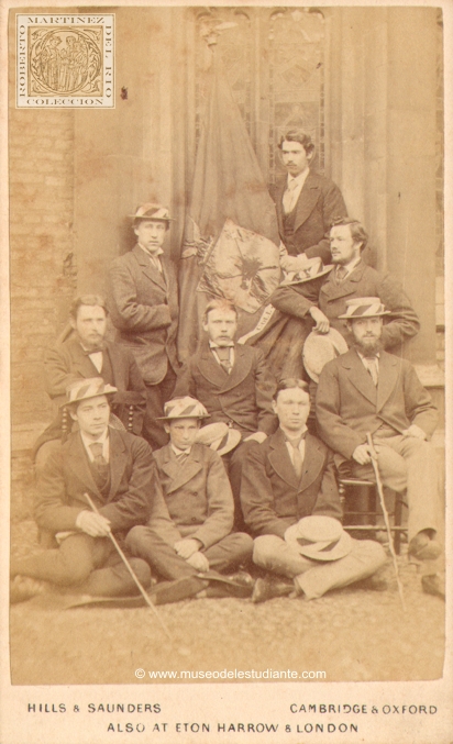 Un grupo de estudiantes junto a la bandera del Queen's College de Cambridge